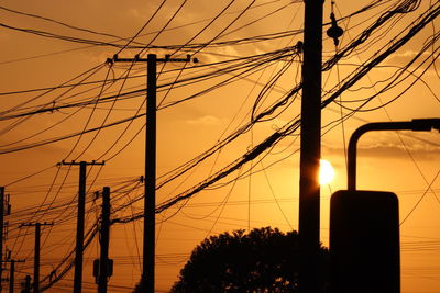 Low angle view of silhouette electricity pylon against sky during sunset