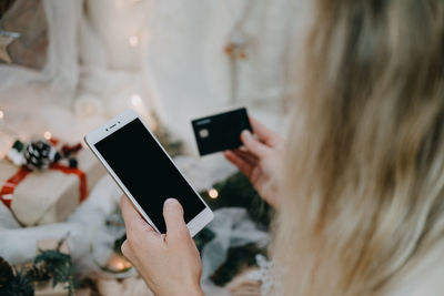 Cropped image of woman holding credit card and mobile phone