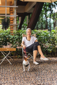 Woman sitting with her chihuahua dog with leash in outdoors cafe.