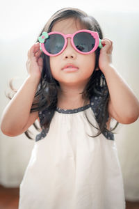 Portrait of cute girl standing against curtain