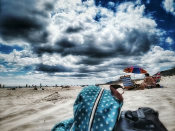 People on beach against cloudy sky