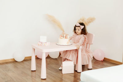 Happy little girl with a birthday cake at the table.