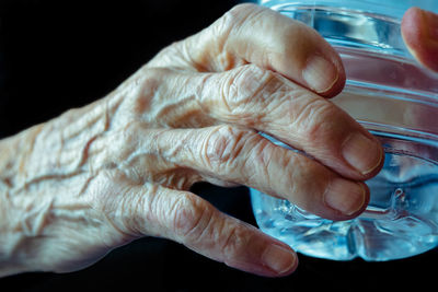 Close-up of hand holding cigarette over black background