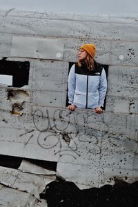 Woman with umbrella standing against wall
