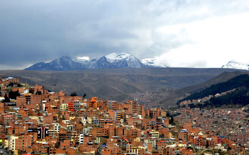 Aerial view of townscape and mountains against sky