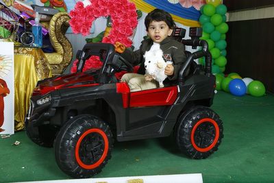 Cute boy sitting in toy car