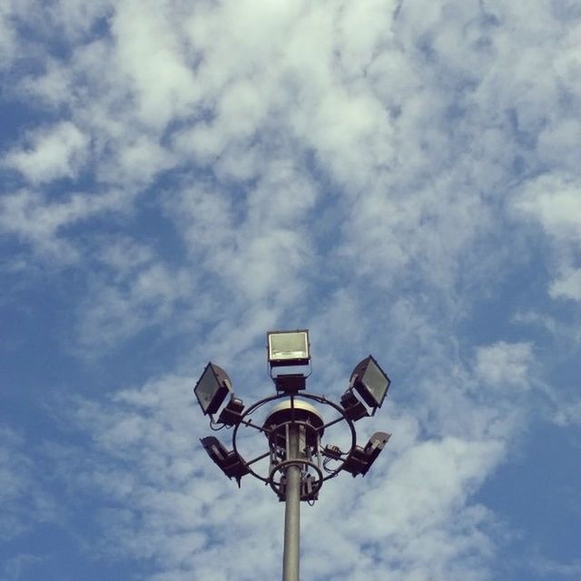 low angle view, sky, lighting equipment, street light, cloud - sky, cloudy, cloud, built structure, pole, lamp post, no people, outdoors, blue, communication, electric light, day, architecture, high section, electricity, nature
