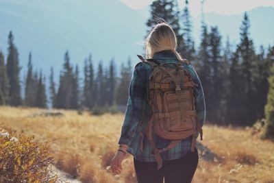 A young and married woman carries a backpack through the mountain fields during a hike