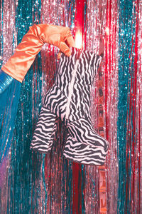 Cropped image of hand holding zebra pattern boot against tinsel decoration