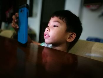 Close-up of boy using smart phone while sitting at table