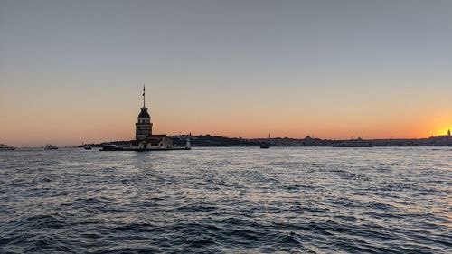 View of building by sea against sky during sunset