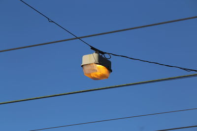 Low angle view of illuminated lamp against clear blue sky
