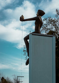 Low angle view of shirtless man sculpture against sky