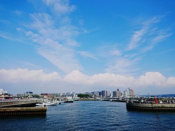 Scenic view of sea and a harbor by buildings against sky