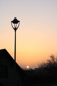 Street light and silhouette building against sky during sunset