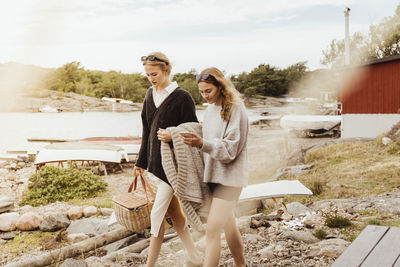 Young woman walking with female friend using mobile phone at harbor