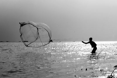 Silhouette man in sea against sky