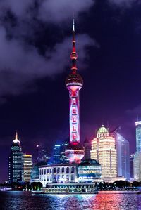 Illuminated buildings in city against sky at night