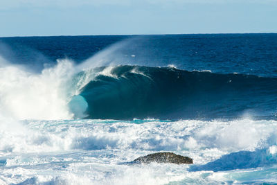 Waves splashing in sea against clear sky