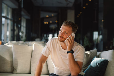 Young man looking away while sitting at home