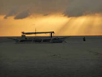 Silhouette boat sailing on beach against sky during sunset