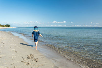 Rear view of man on beach against sky