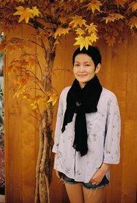 Portrait of smiling girl standing against tree during autumn