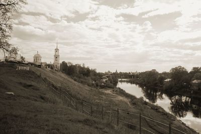 View of bridge over river and buildings against cloudy sky