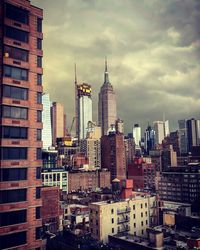 Modern buildings in city against cloudy sky