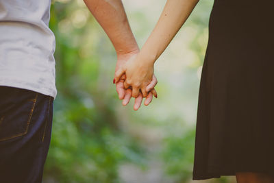 Rear view of man and woman holding hands