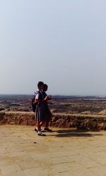 Woman standing on landscape against clear sky