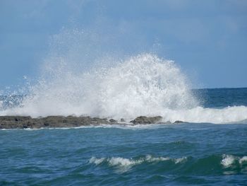 Waves splashing on sea against sky