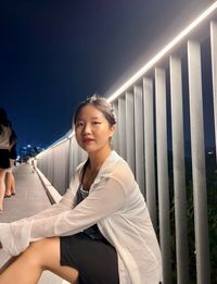 Portrait of young woman sitting by railing