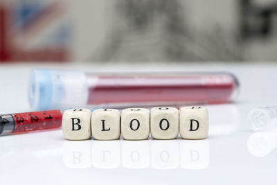 Close-up of toy blocks with text by syringe with blood on table