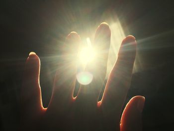Close-up of hand holding illuminated lights against bright sun