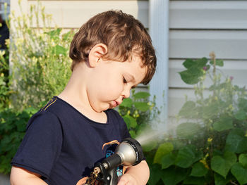 Little boy playing with a watering hose in the backyard