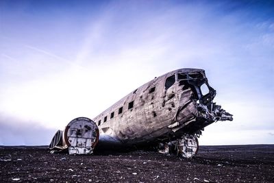 Abandoned airplane at beach against sky