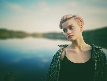 Portrait of young woman standing by lake