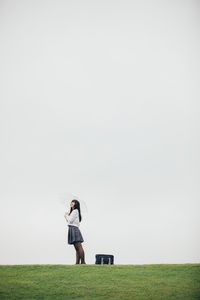 Full length of man standing on field against clear sky