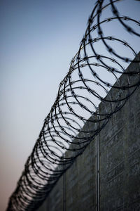 Low angle view of barbed wire fence against sky