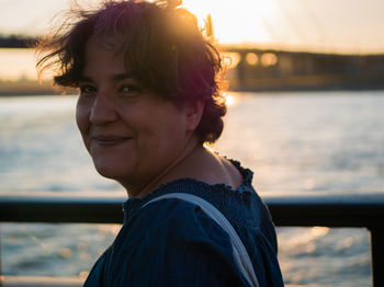 Side view portrait of smiling mature woman by sea during sunset