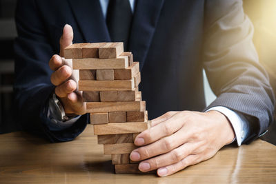 Midsection of businessman holding stacked dominoes