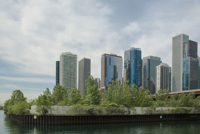 Skyscrapers by river against sky