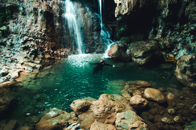 High angle view of man swimming in pond against waterfall