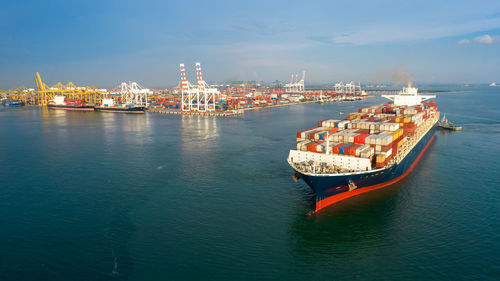 Aerial in front of smart cargo ship carrying container and running near international custom 