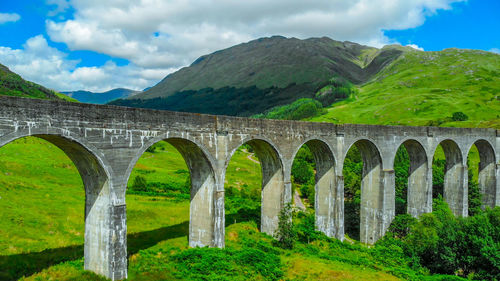 Arch bridge in mountains against sky