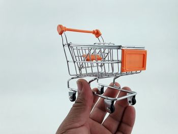 Close-up of hand holding shopping cart against white background