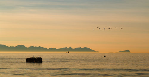 Silhouette of boat in sea against mountain in background