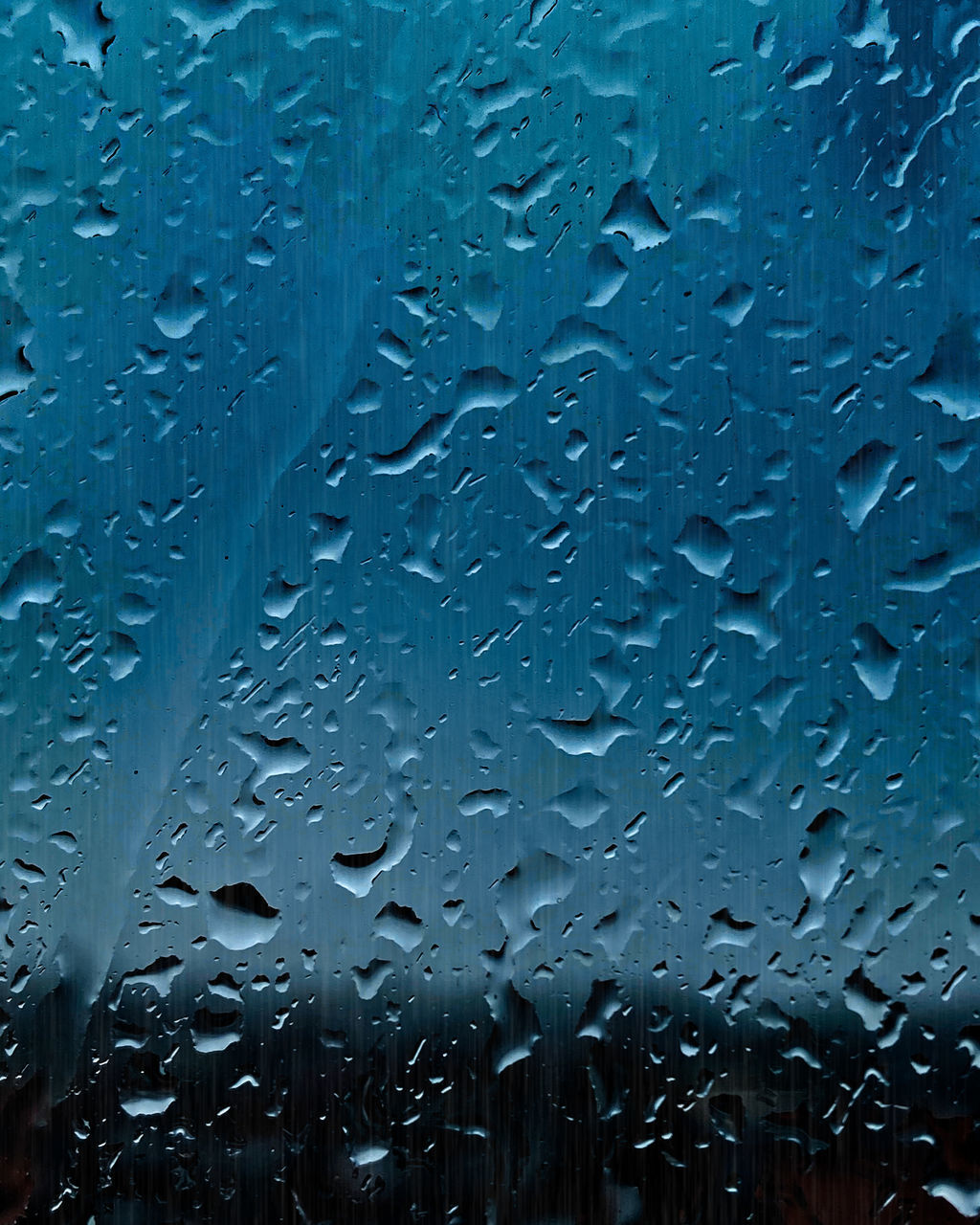 CLOSE-UP OF RAINDROPS ON GLASS WINDOW