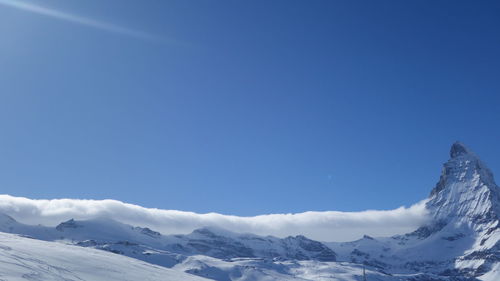 Scenic view of snowcapped mountains against clear blue sky